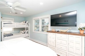 A bedroom with bunk beds, a ceiling fan, a TV, and a dresser. - Shoreside Cottage - Classic 2 BR Beauty - Amazing Views from Covered Porch! Dog (Surf City)