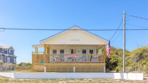 A single-story house with a porch, a small deck, and an American flag. - Shoreside Cottage - Classic 2 BR Beauty - Amazing Views from Covered Porch! Dog (Surf City)