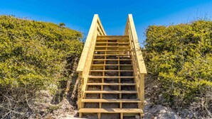 A wooden staircase leading up a sandy slope, surrounded by dense shrubbery. - Shoreside Cottage - Classic 2 BR Beauty - Amazing Views from Covered Porch! Dog (Surf City)