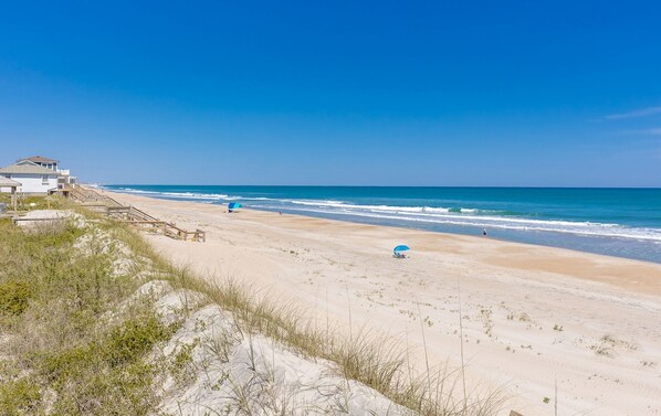 Une plage avec une structure en bois, un ciel dégagé et l’océan.