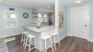 A kitchen with a central island, white bar stools, and a 'For Sale' sign. - Shoreside Cottage - Classic 2 BR Beauty - Amazing Views from Covered Porch! Dog (Surf City)
