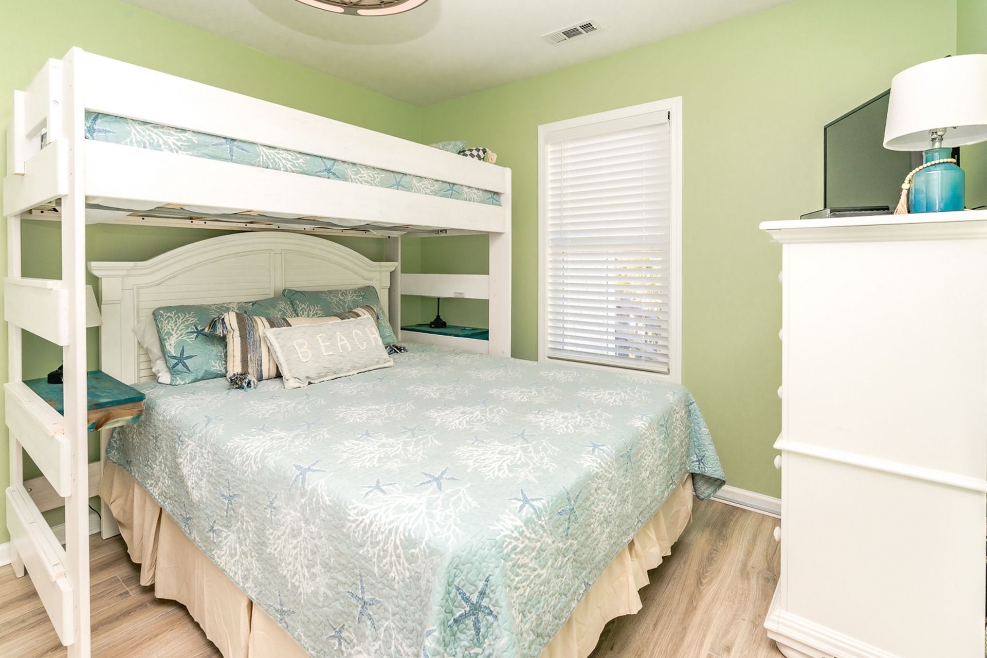 Una cama individual con cabecera decorativa, una mesita de noche y un aparador con lámpara.