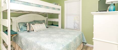 Una cama individual con cabecera decorativa, una mesita de noche y un aparador con lámpara.