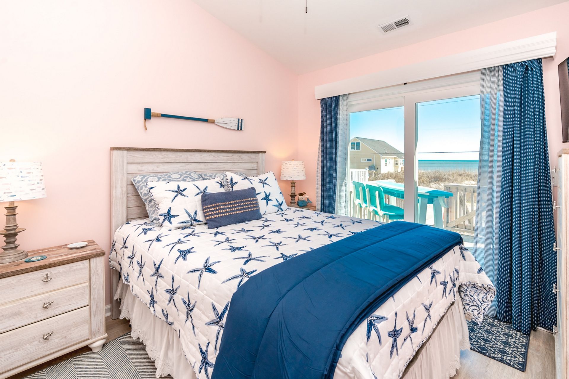 A bedroom with a bed, a nightstand, a dresser, and a window with curtains.