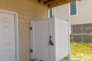 A white portable toilet unit with a hinged door, a metal latch, and a small step at the base.