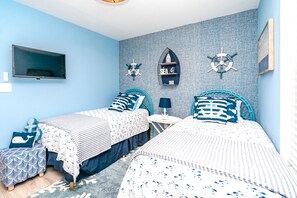 Une chambre avec deux lits, une télévision et une décoration sur le thème de la marine.