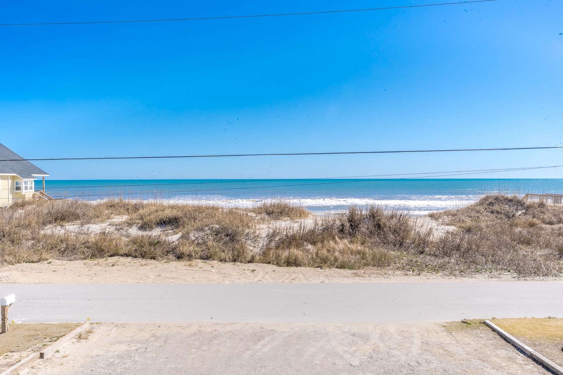 Vista sulla spiaggia con una casa e una strada in primo piano.