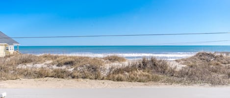 A beach view with a house and a road in the foreground.