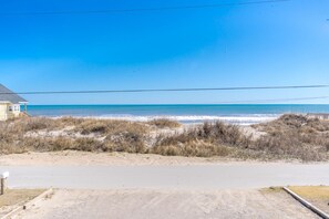 Une vue sur la plage avec une maison et une route au premier plan.
