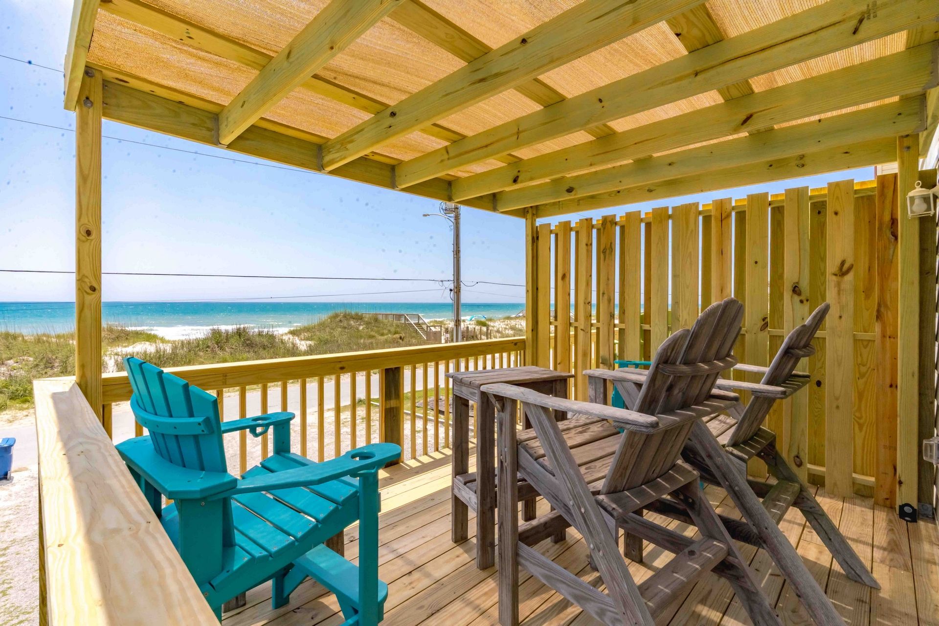 A wooden deck with a view of the beach, featuring a table and chairs.
