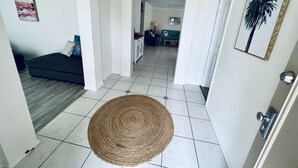 Un couloir avec un tapis tissé, un canapé foncé et, au fond, un canapé de couleur turquoise.