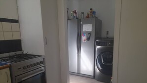 Una cocina con estufa a gas, horno, refrigerador y lavadora.