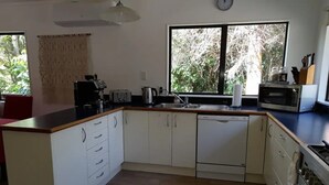 Una cocina moderna con gabinetes blancos, lavavajillas, microondas y un fregadero.
