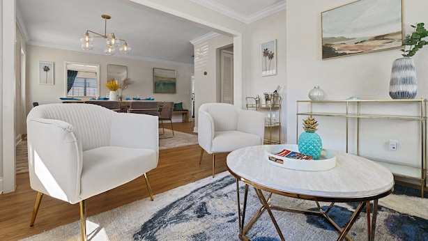 Una sala de estar moderna con una mesa redonda, dos sillones blancos y un comedor con una mesa y sillas de madera.