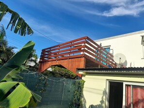 A modern building with a wooden bridge structure, a satellite dish, and a white exterior.