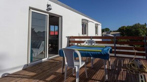 Eine Holzterrasse mit Tisch, Stühlen und einer Sitzbank, sowie ein Schiebetürglas.