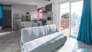 Eine moderne Küche mit Kühlschrank, Mikrowelle und Herd, ein Essbereich mit Tisch und Stühlen sowie ein Balkon mit Blick.