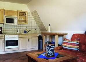 Enjoy a casual dining experience in this kitchen with a microwave, oven, and sink, plus a chalkboard menu on a wooden table.