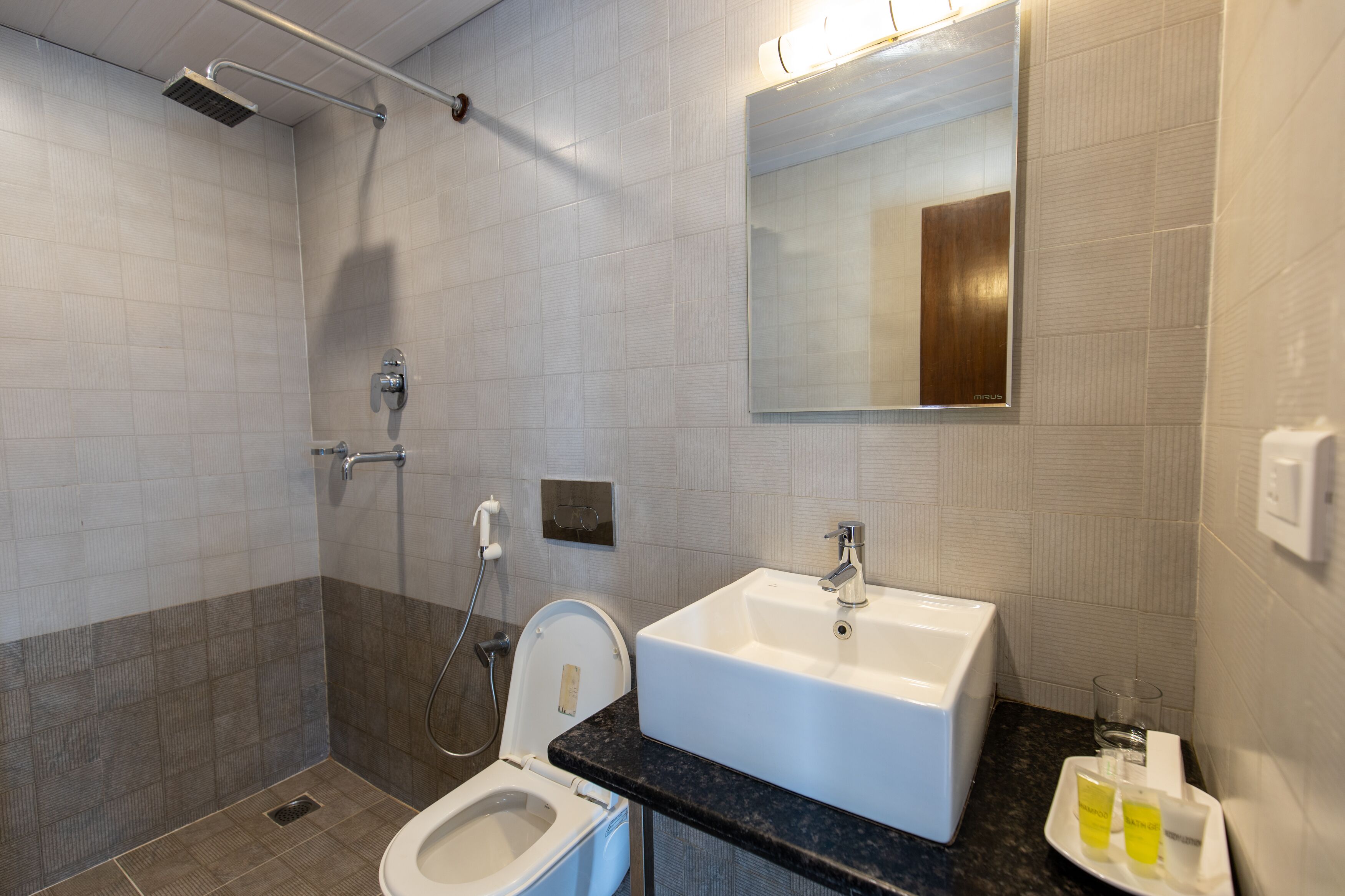Une salle de bain moderne équipée d’une douche, de toilettes, d’un lavabo et d’un miroir.
