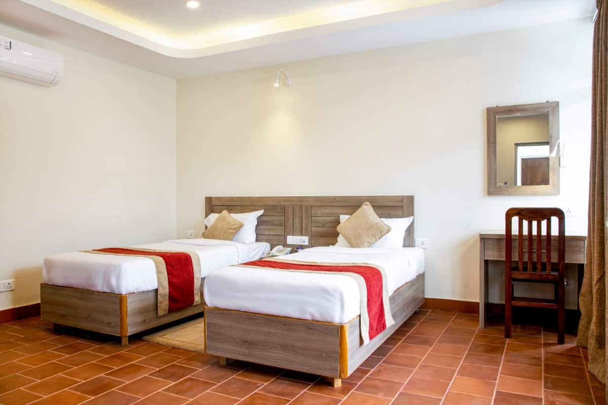 Ein Hotelzimmer mit zwei Betten, einem Schreibtisch, einem Stuhl und einem Spiegel.