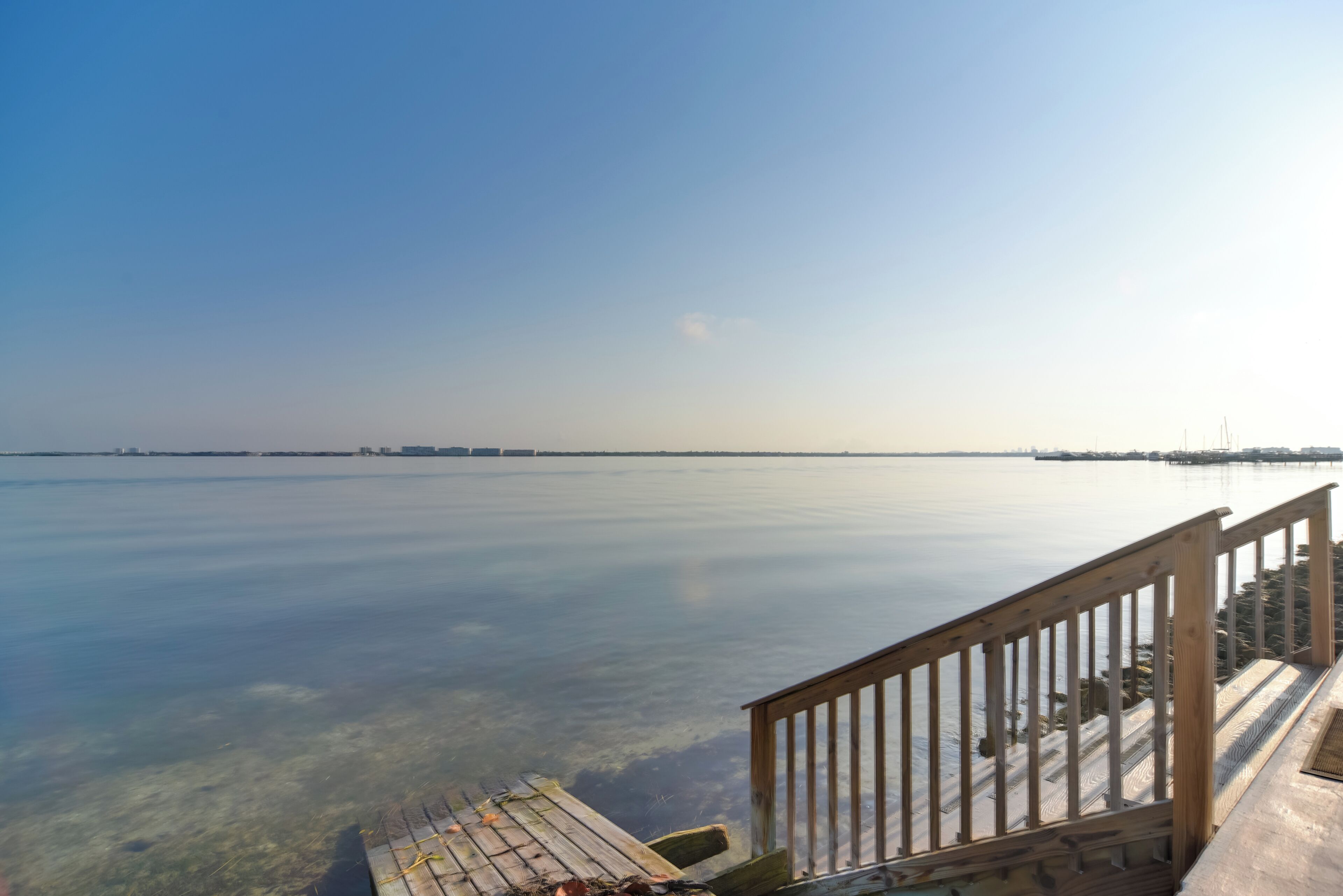 A wooden pier extending into calm water with a clear sky above.