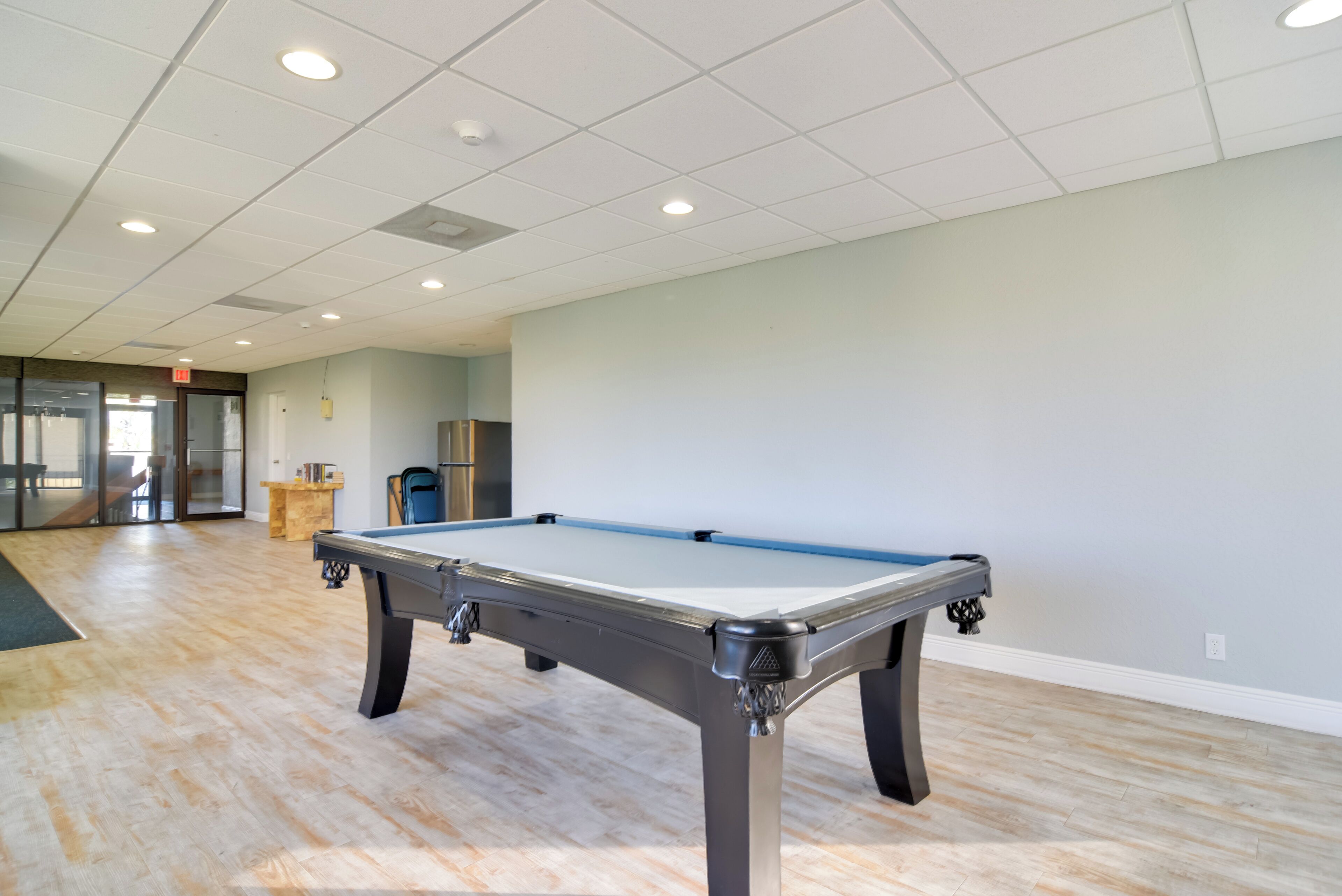 A pool table in a room with wooden flooring and white walls.