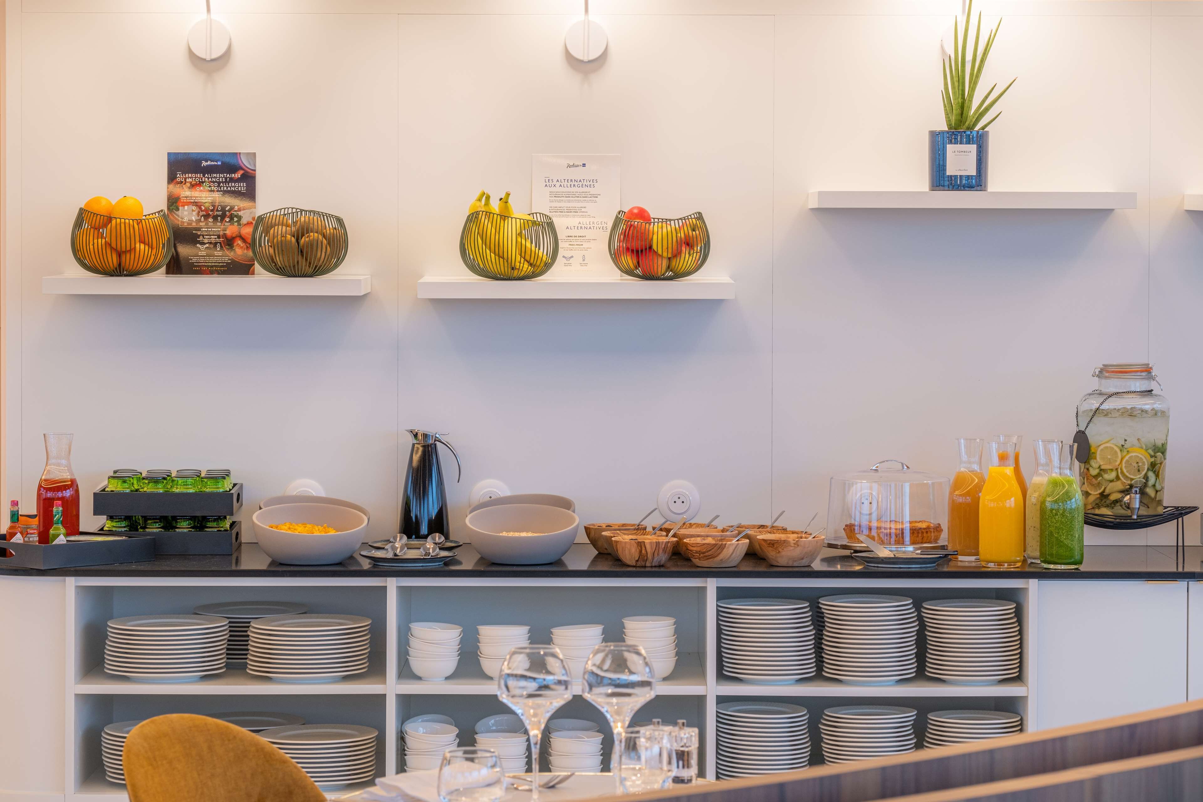 A buffet setup with various food items and beverages, including fruits, salads, and drinks.