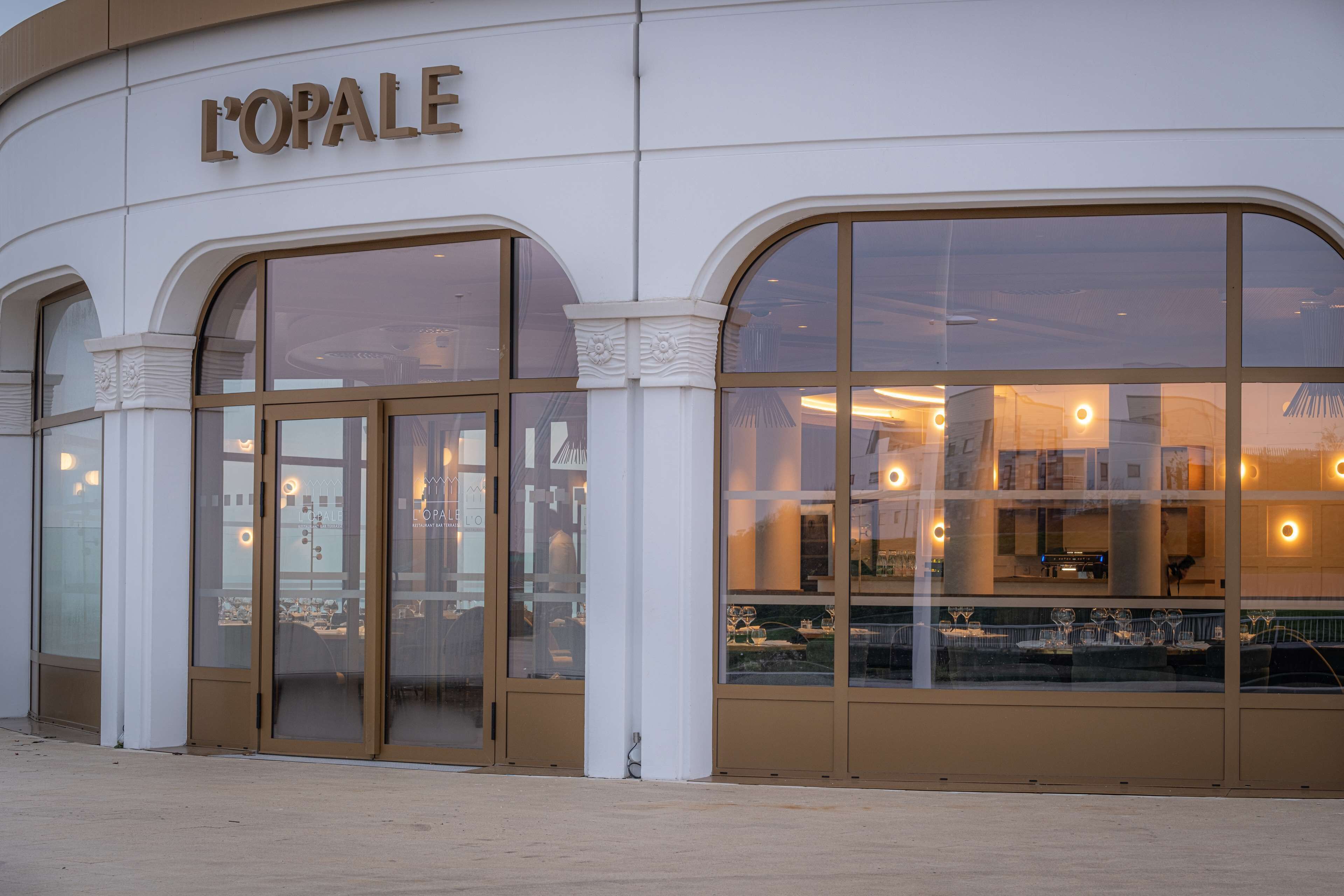 Un edificio con amplias ventanas arqueadas y un letrero que dice "L'OPALE".