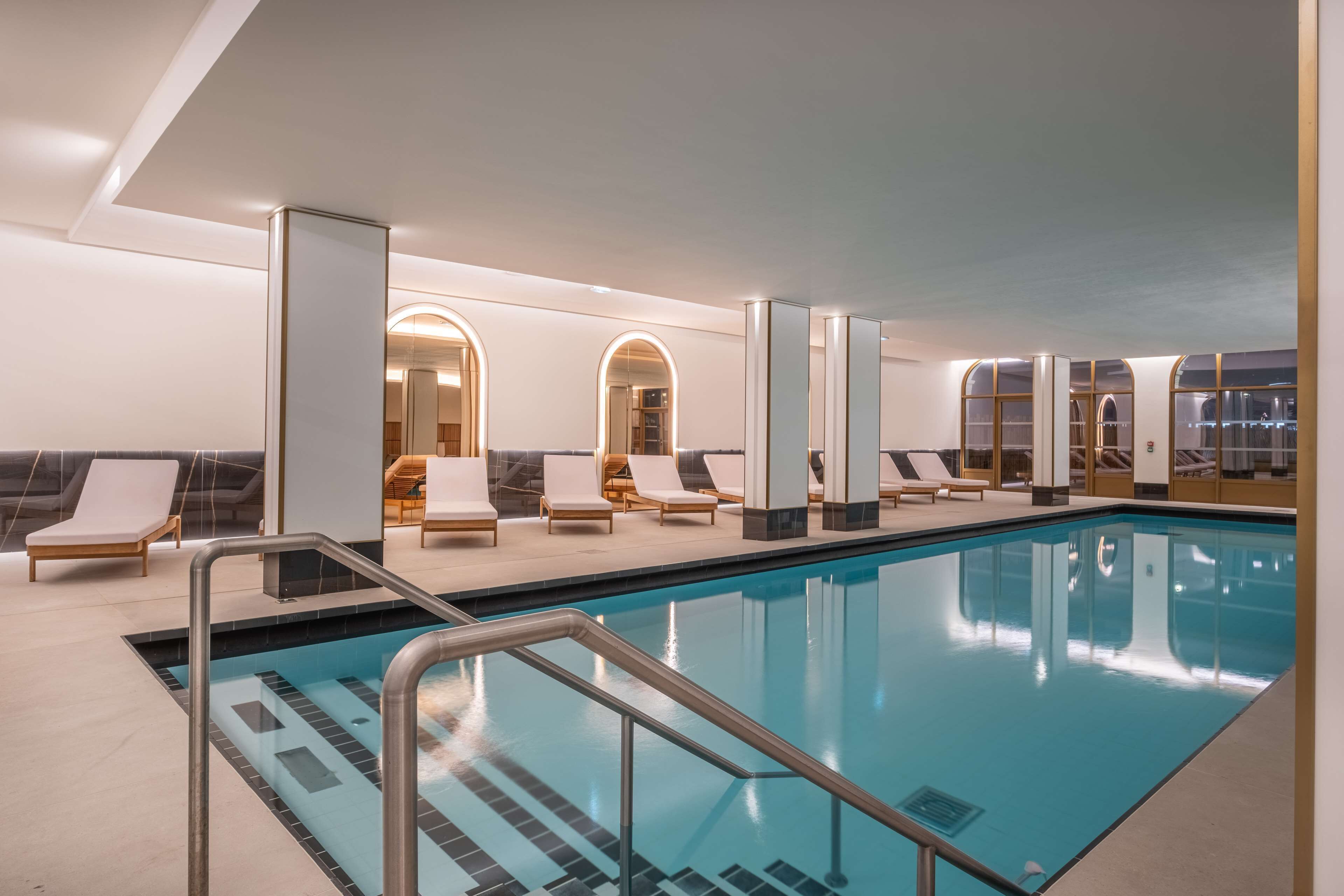 An indoor swimming pool with lounge chairs and a modern interior design.