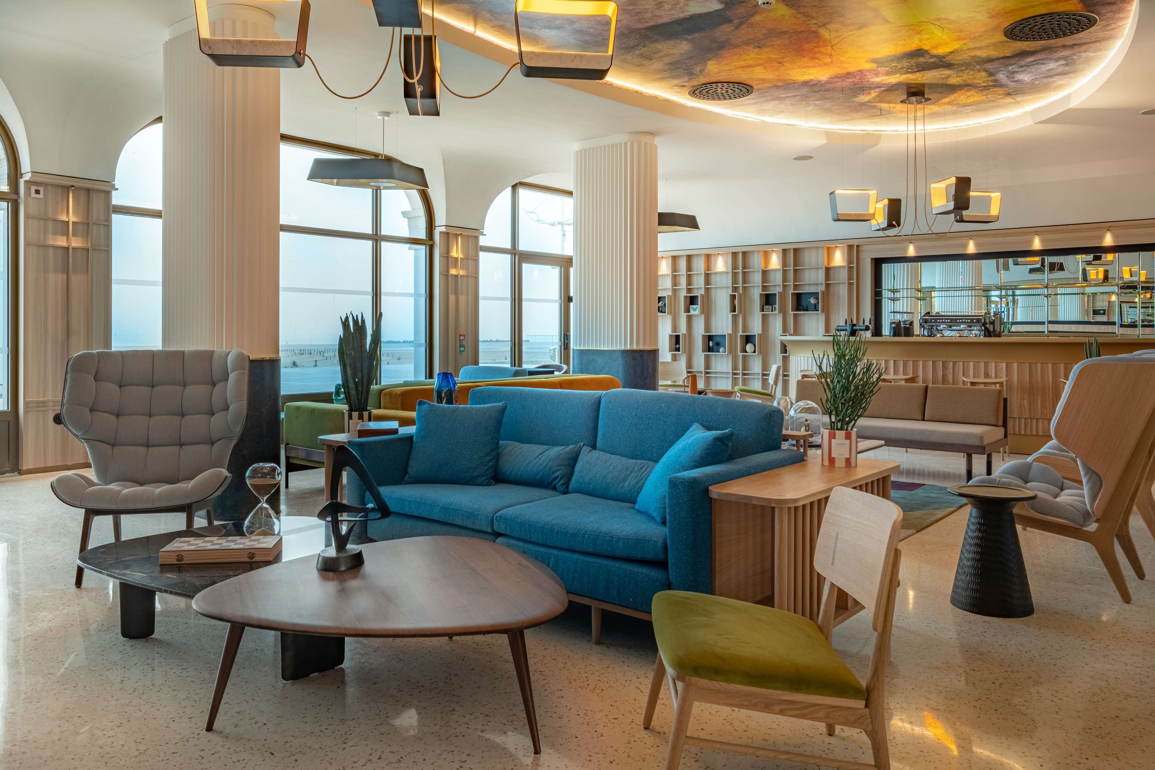 A spacious lounge area with a blue sofa, a grey armchair, and a wooden coffee table.