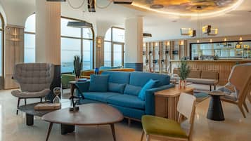 A spacious lounge area with a blue sofa, a grey armchair, and a wooden coffee table.