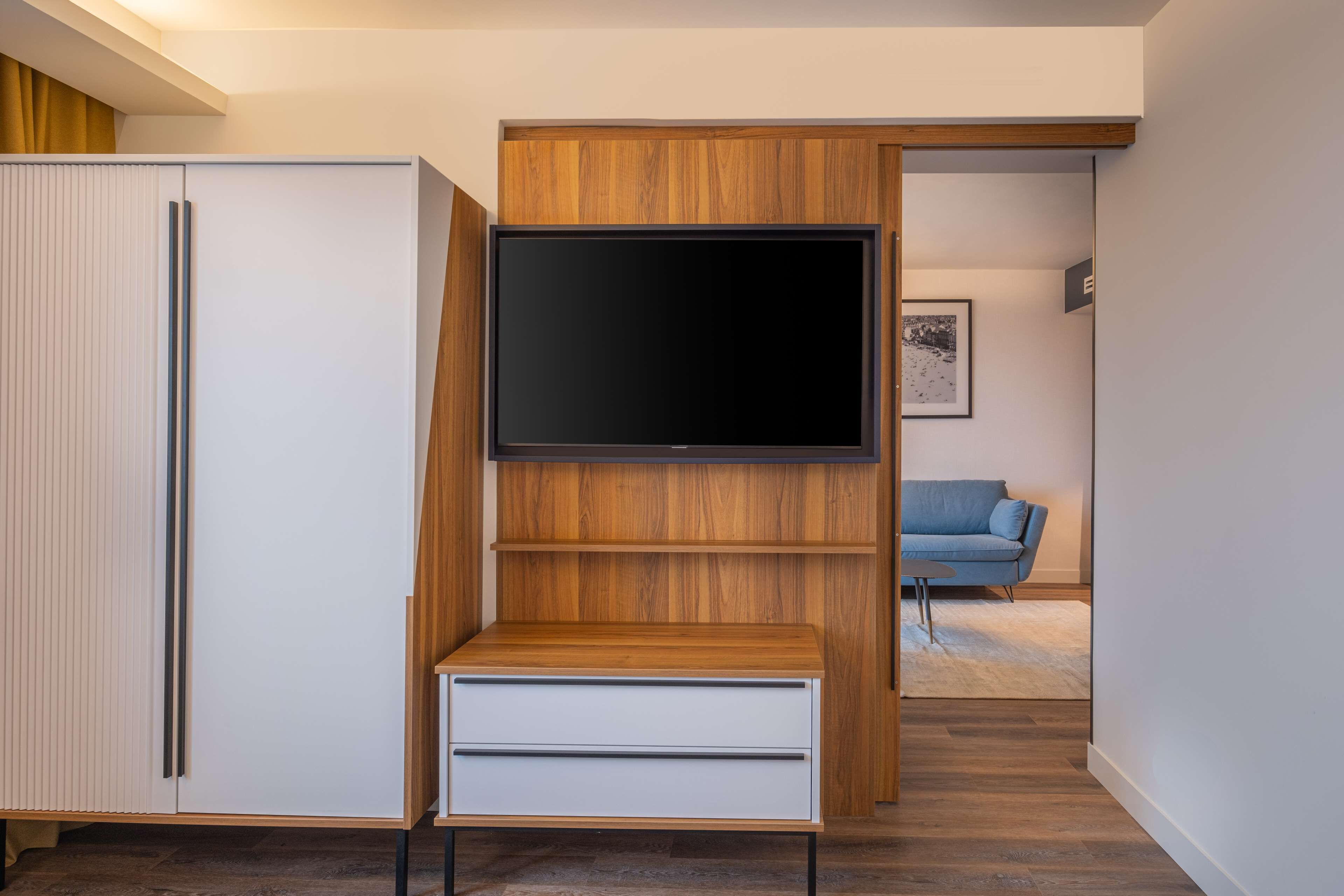 A modern living room with a built-in TV, a white cabinet, and a blue sofa.
