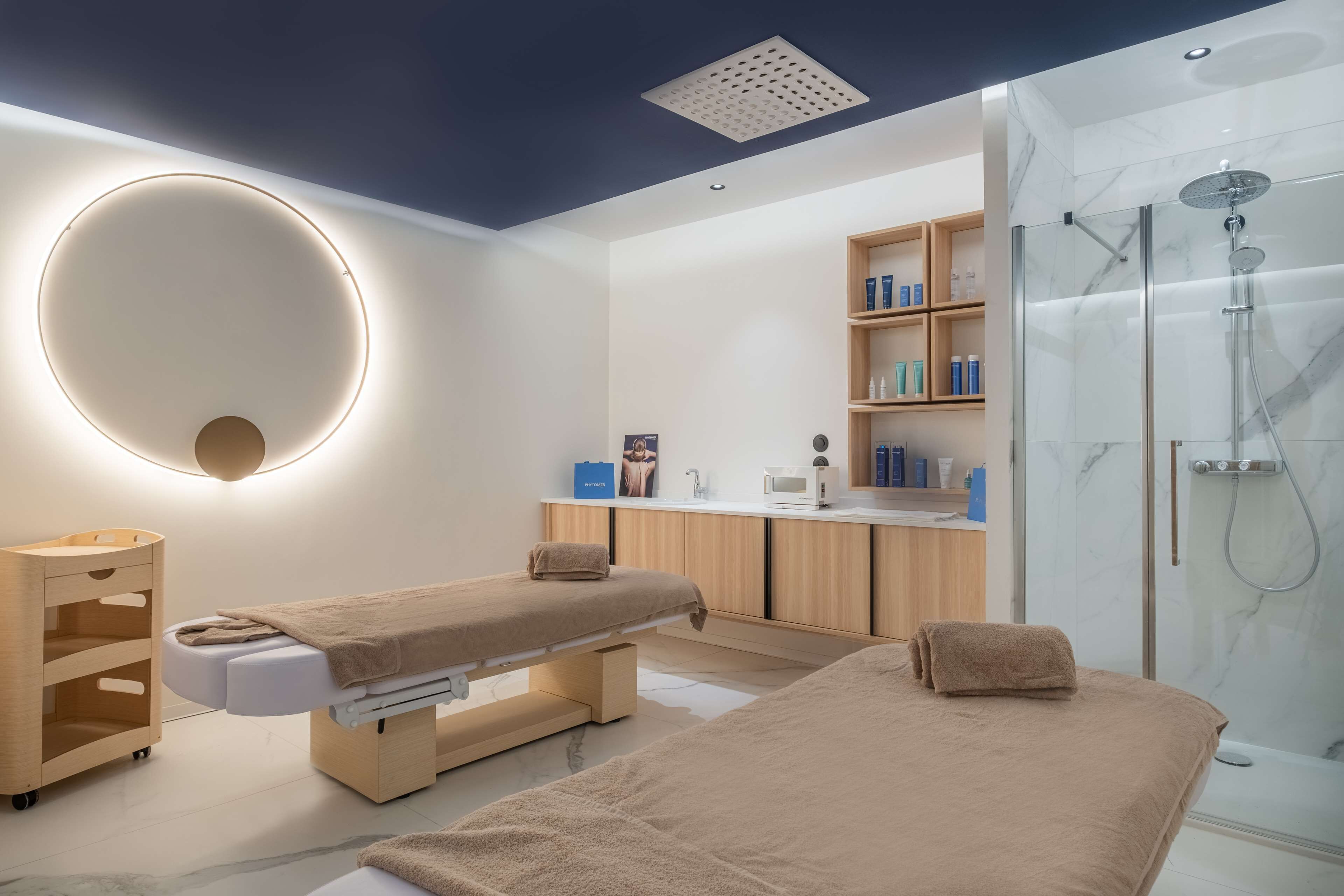 Un spa moderno con una camilla de masaje, zona de ducha y tocador con estantes llenos de artículos de aseo.