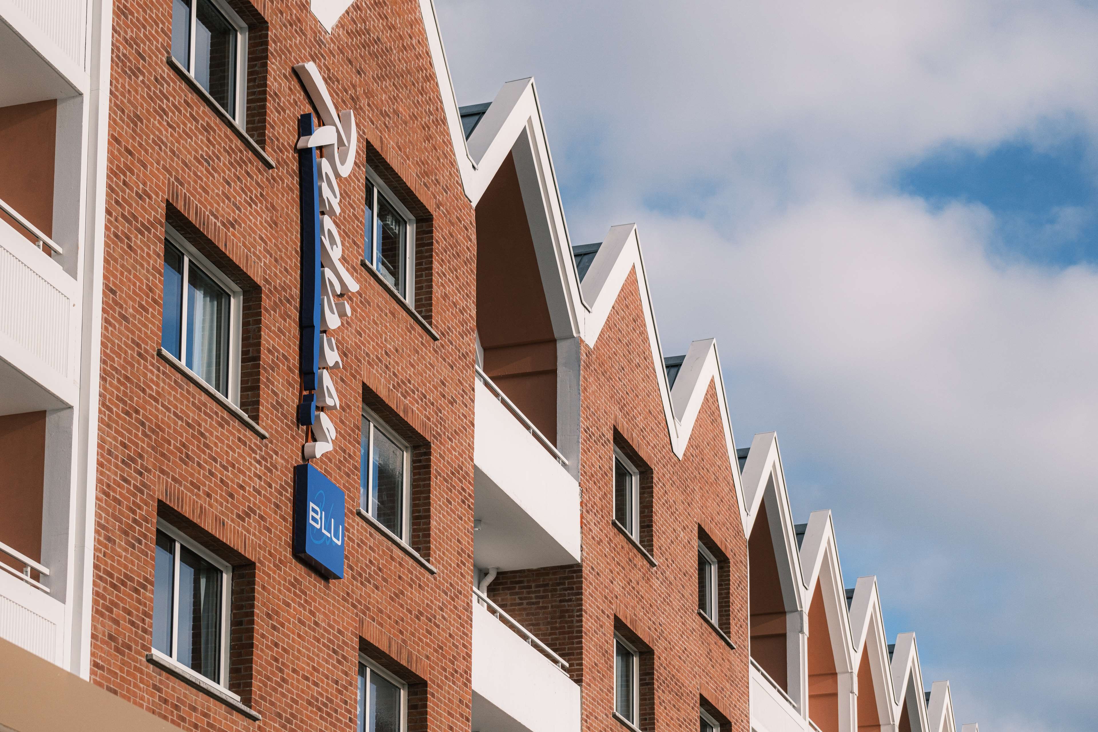 A row of red brick buildings with balconies and a sign that reads "Blu".