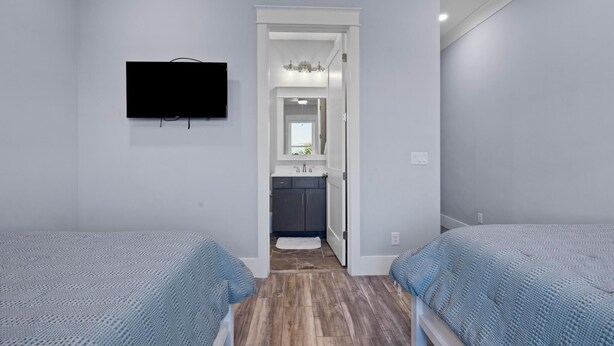 Un dormitorio con dos camas, un televisor y un baño visible a través de una puerta abierta.