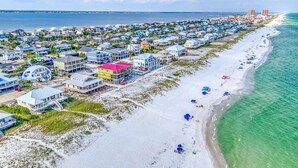 Una zona residencial costera con propiedades frente a la playa, una playa de arena y vista al océano.