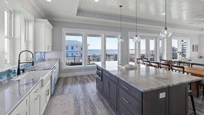 Cocina moderna con una isla grande, electrodomésticos integrados y amplios ventanales con vistas al océano.