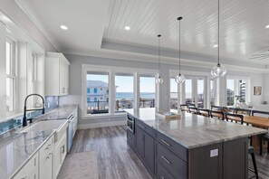 A modern kitchen with a large island, built-in appliances, and large windows offering ocean views. - Beautiful Gulf View Home | Private (heated) Pool | Event Friendly | Sleeps 24 (Pensacola Beach)