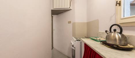 A narrow kitchen with a white refrigerator, a white oven, and a red curtain.