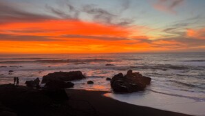 Une plage avec des rochers et un coucher de soleil.