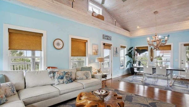 A spacious living room with a sofa, coffee table, and dining area. - The Nautilus (Tybee Island)