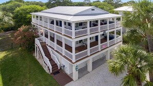 A two-story house with a balcony on each floor, surrounded by greenery. - The Nautilus (Tybee Island)