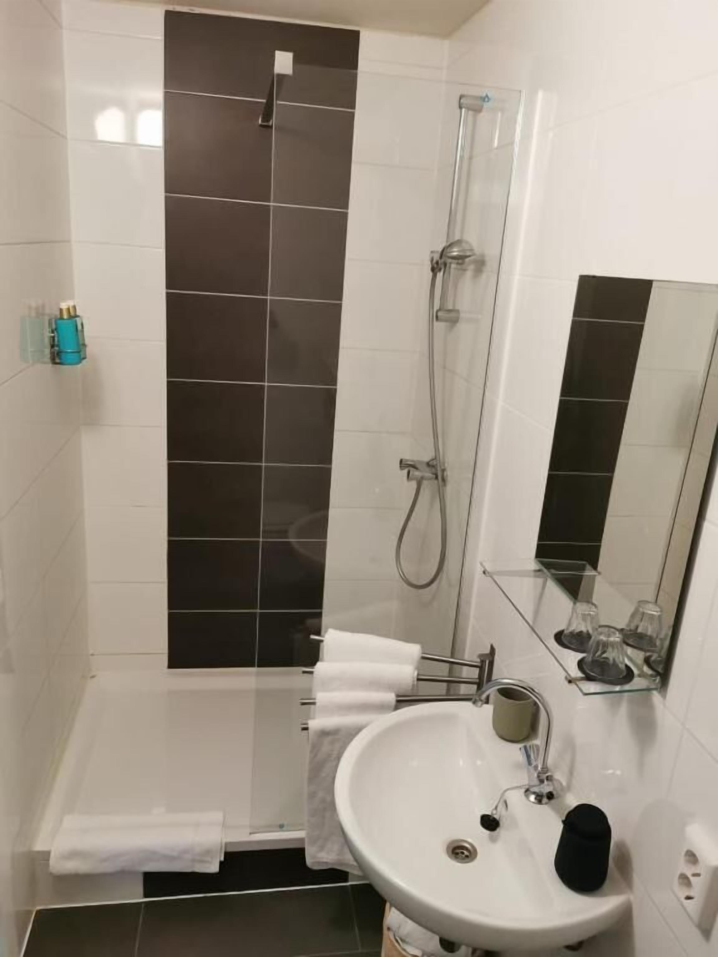 A bathroom with a shower, a sink, and a mirror.