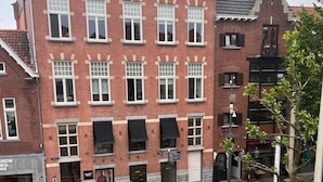 A red brick building with multiple windows and a ground-floor shop. There are outdoor tables and chairs in front of the building. - Milk and Cookies (Venlo)