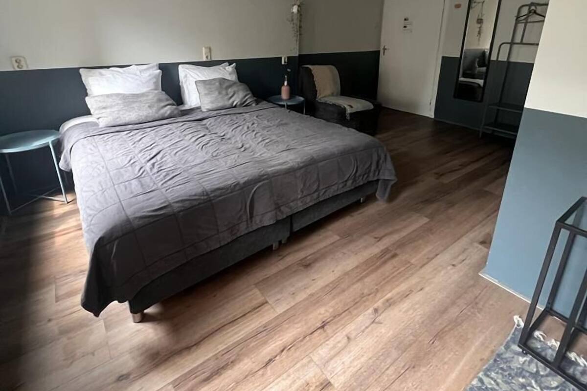 A bedroom with a large bed, bedside tables, a mirror, and a wardrobe.