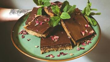 Een bord met chocoladegedekte desserts, versierd met muntblaadjes en rozenblaadjes.