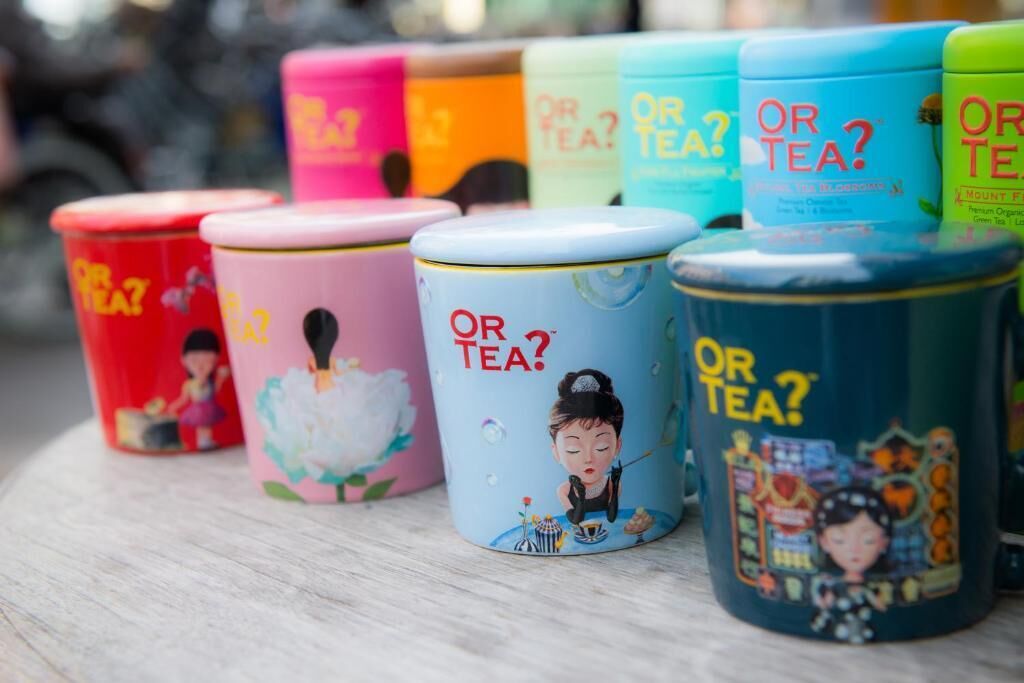 A row of colorful tea tins with the text "OR TEA?" and illustrations of a woman in various poses.