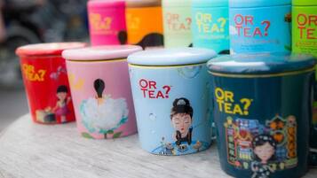 A row of colorful tea tins with the text "OR TEA?" and illustrations of a woman in various poses.