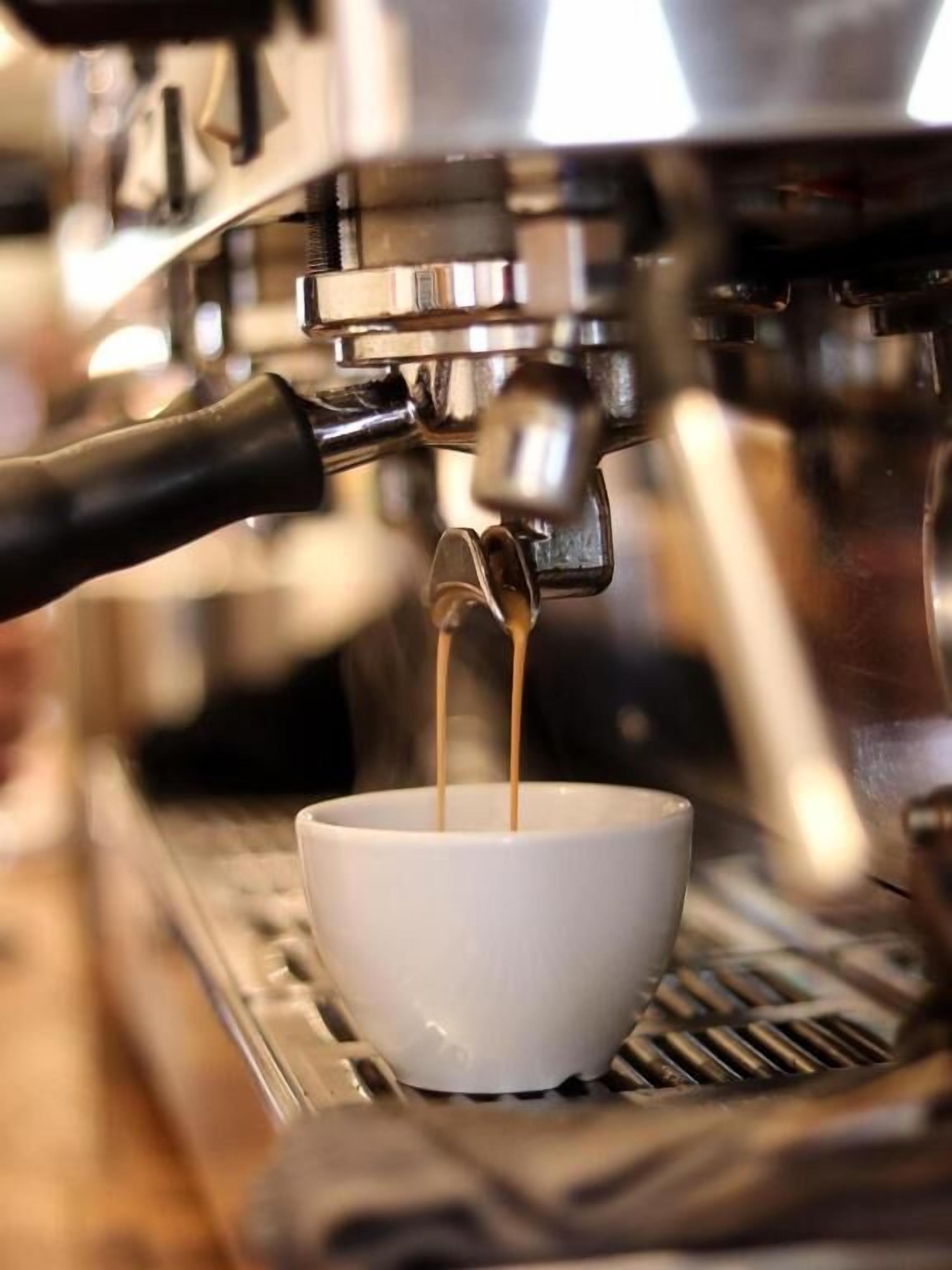 Een koffieapparaat schenkt espresso in een kopje.