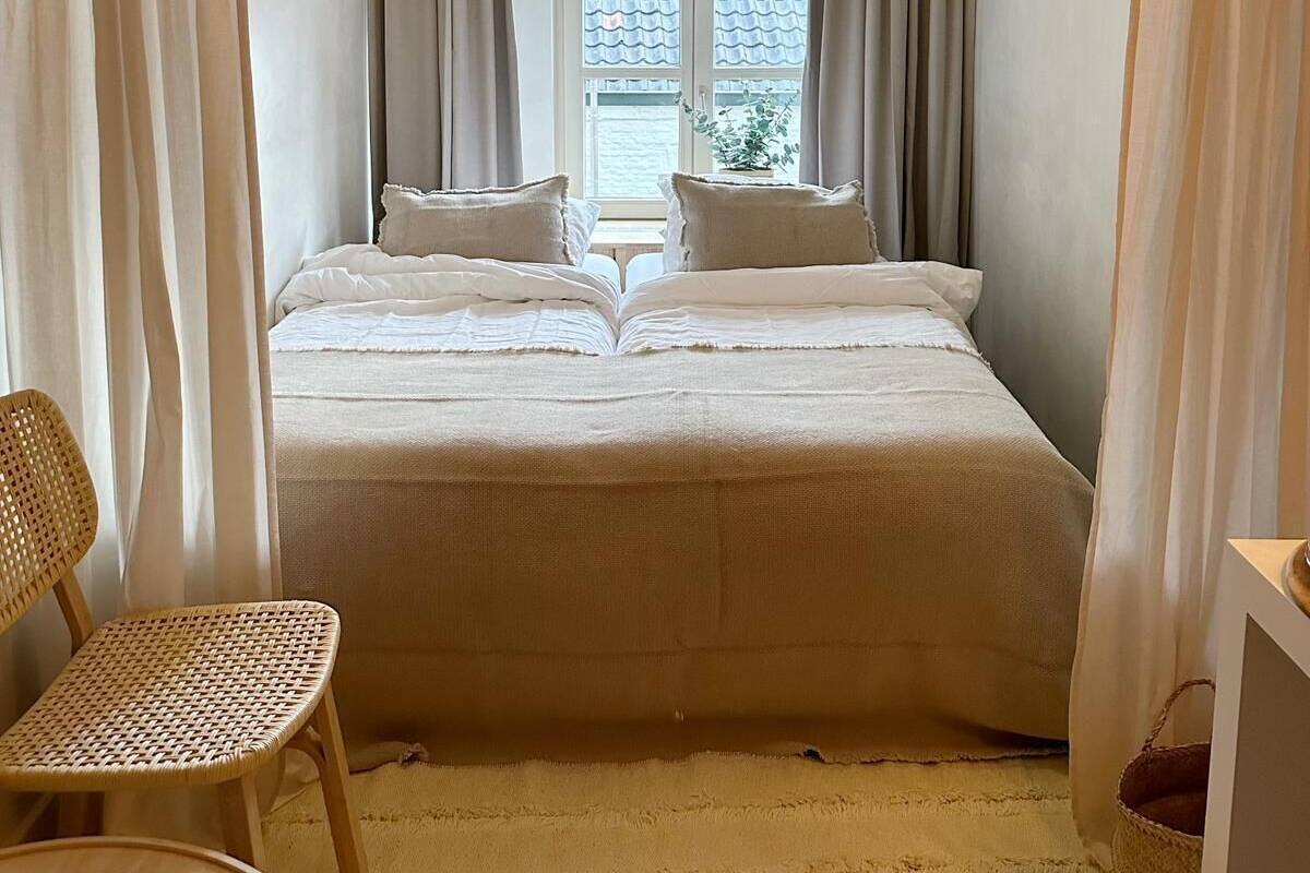 A bedroom with a bed, curtains, a window, and a chair.